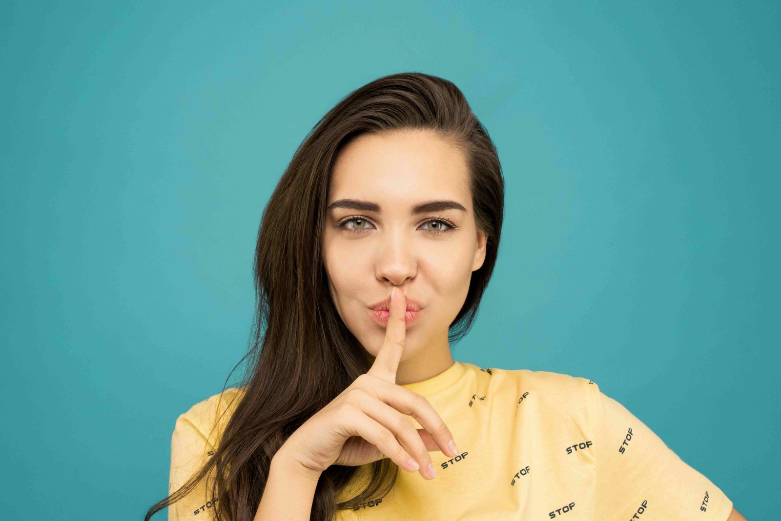 Frau mit vollem Haar hält Zeigefinger vor den Mund, als Zeichen für Geheimnis. Sie trägt ein Shirt mit dem Schriftzug "Stop". Unsere gemeinsame Mission: Deinen Haarausfall stoppen! Denn mittlerweile gibt es diverse Möglichkeiten, um Haarausfall effektiv zu bekämpfen. In 3 einfachen Schritten finden wir deine Lösung und verraten kurz und knapp, was du wissen musst.