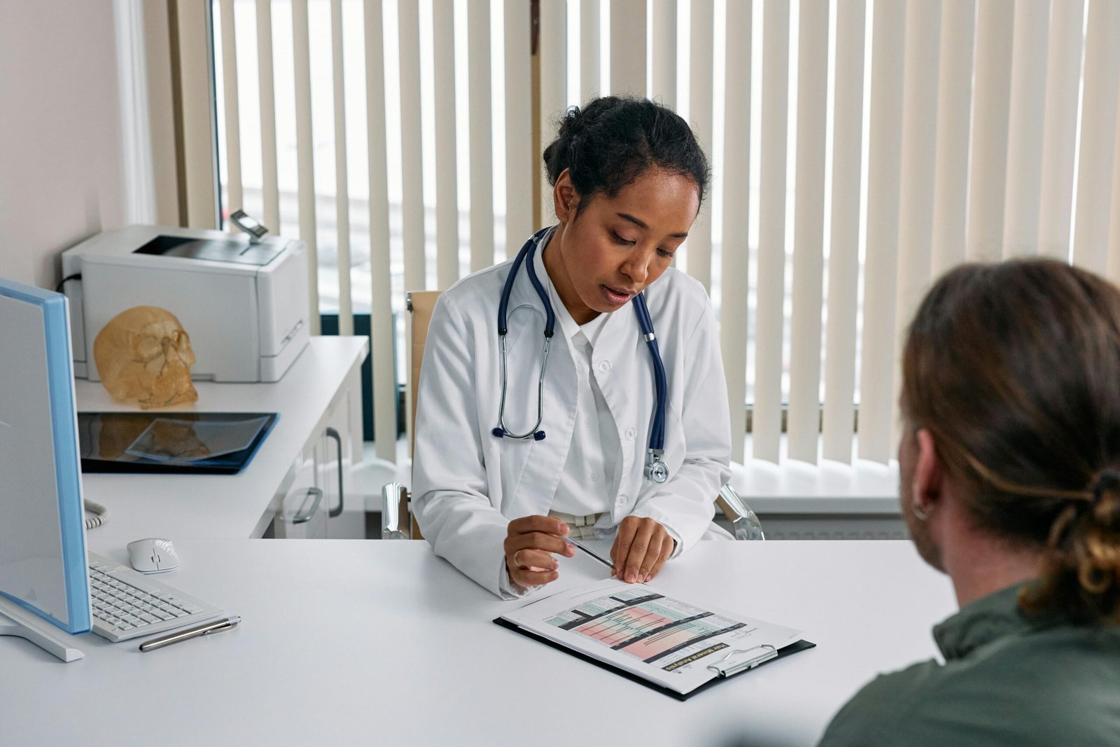 Eine Ärztin im Gespräch mit einem Patienten in mittlerem Alter. Es zeigt, dass das Ansprechen der Probleme der erste Schritt zu Hilfe bei Erektionsstörungen ist.