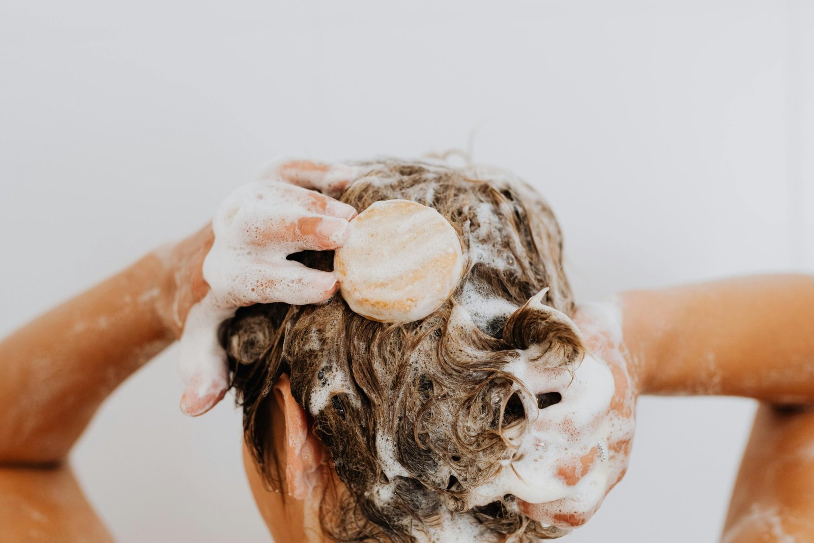 Eine Frau wäscht sich ihre Haare mit Ketoconazol-Shampoo, um mit dem Wirkstoff Ketoconazol gegen Haarausfall zu kämpfen.