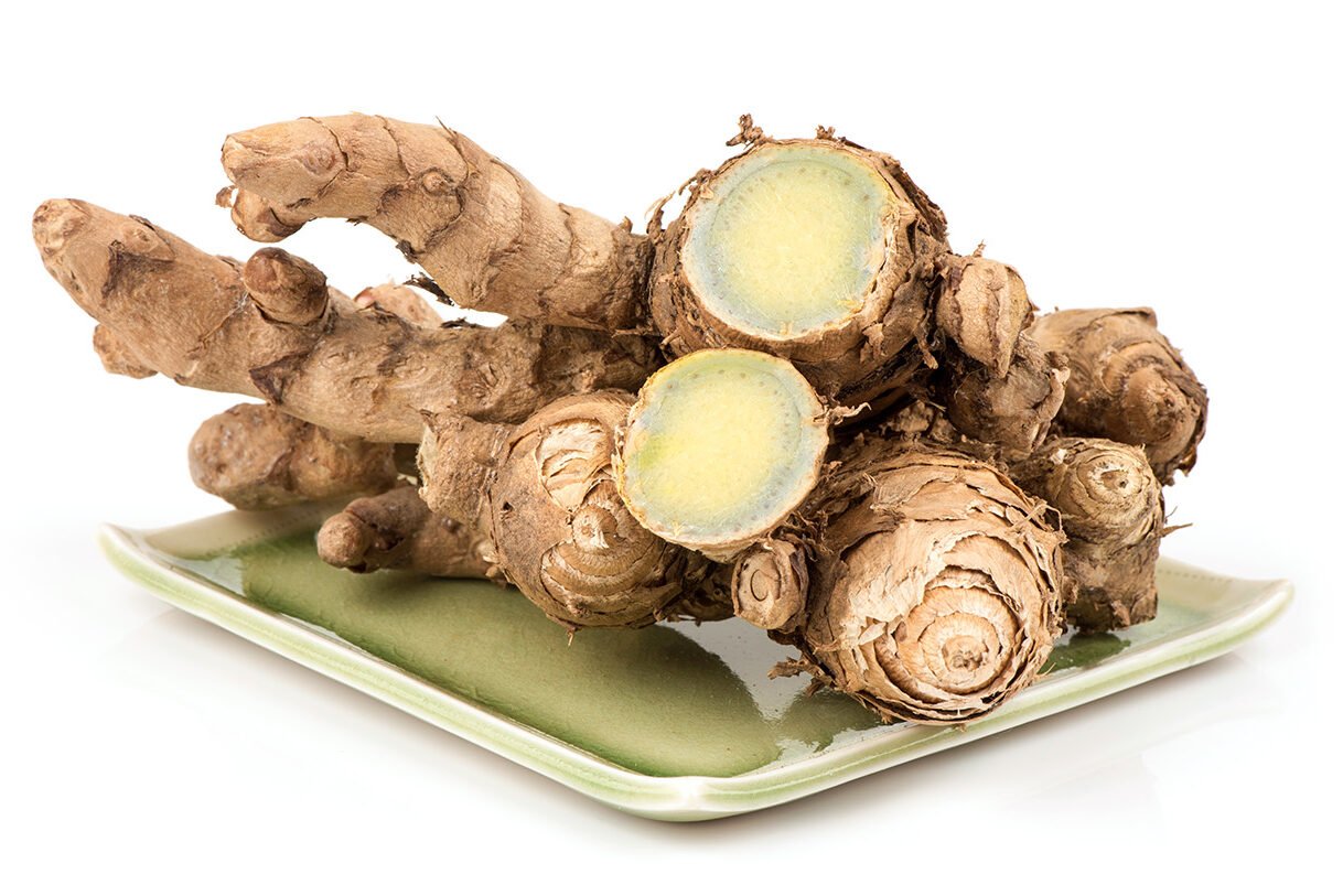 Kurkuma Haare: Frische Wurzeln von Curcuma aeruginosa auf einem grünen Teller, mit hellgelbem und bläulichem Inneren.