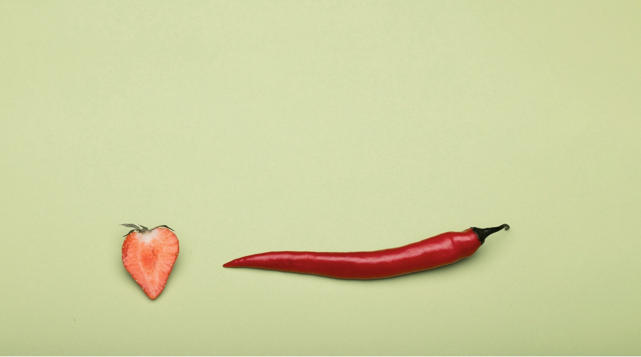 Das Bild zeigt eine halbierte Erdbeere und eine Chili als symbolische Darstellung für Libido.